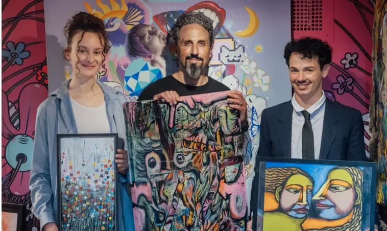 Des artistes posent avec leurs toiles dans la galerie.