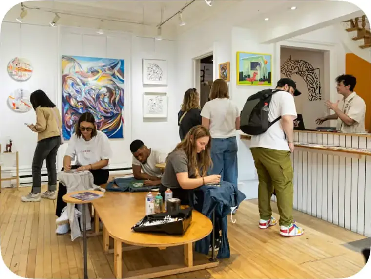 Des visiteurs peignent autour de la grande table de la galerie pendant une soirée cocon.