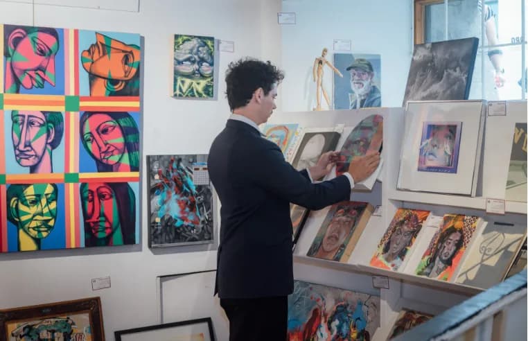 Un visiteur découvre des toiles accrochées dans la galerie.