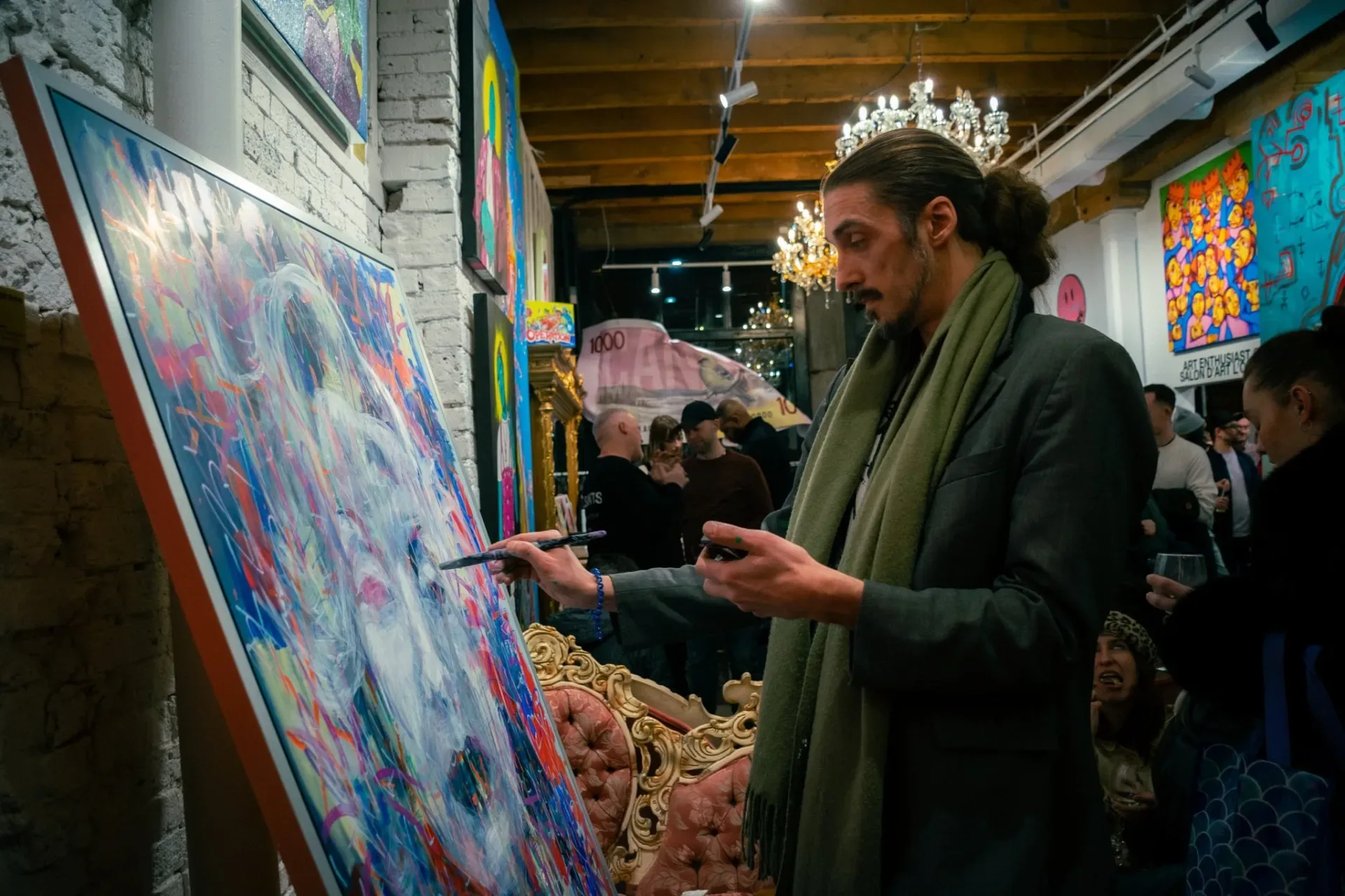 Un artiste peint en direct au milieu des invités lors d'un vernissage.