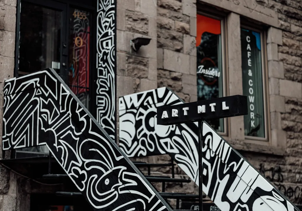 Un escalier extérieur de Montréal peint en noir et blanc, avec une enseigne Art MTL.